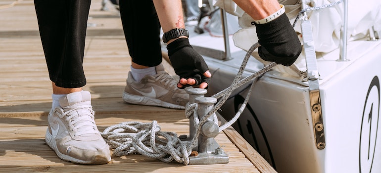 A boat is in the water and a man is tying it to the docks.