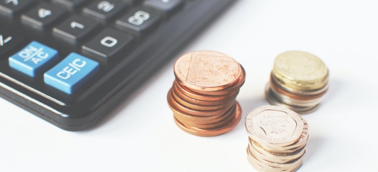 Picture of coins next to a calculator on a white surface 