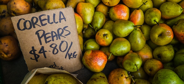 Pears are on a table and there is a sign with a price.