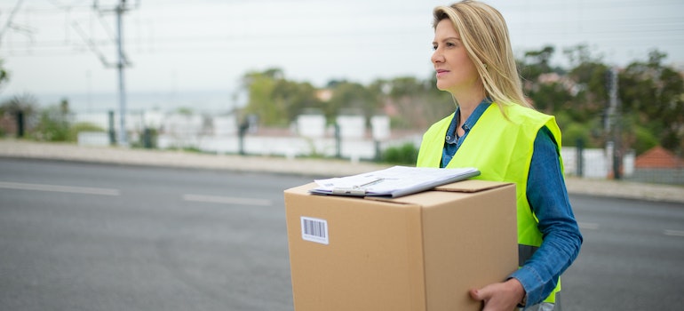 A woman carrying a box, possibly a team at movers Bathesda MD.