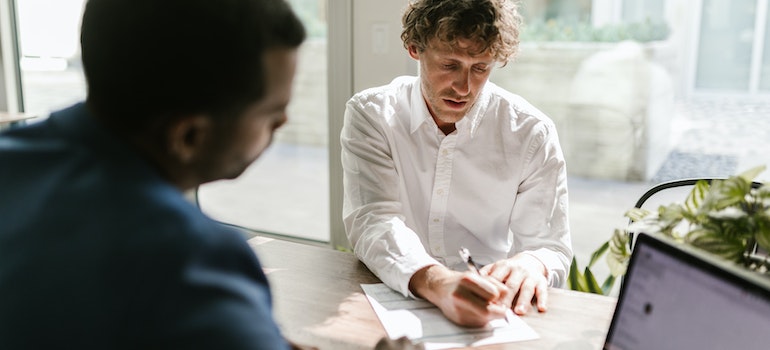 A Man Signing a Document at an Office - time to send complaints to a moving company.