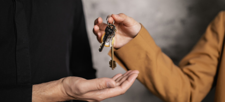 People exchanging house keys after a successful real estate sale, a transaction which can be one of the reasons why seniors move to Bethesda.