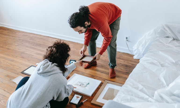 A picture of a couple sorting wall decorations together.