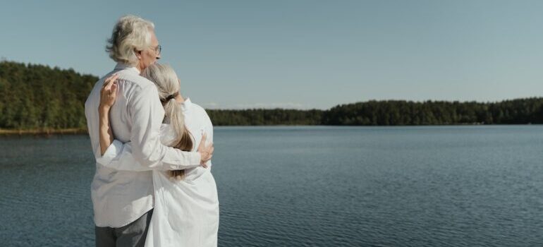 an elderly couple standing beside water