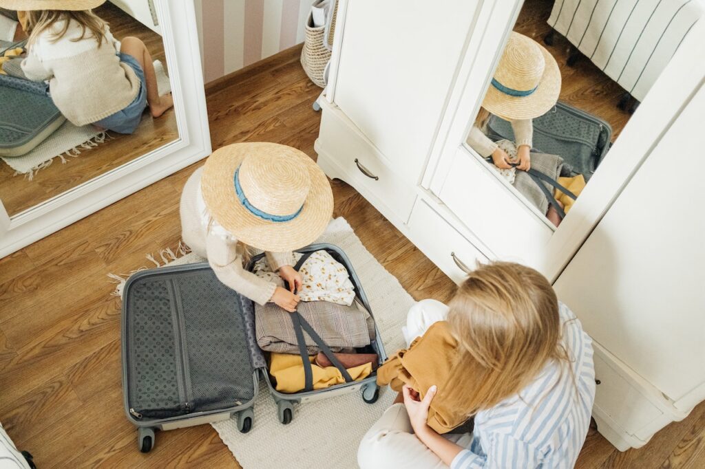 A little girl helping her mother pack a suitcase to help when moving a large family.