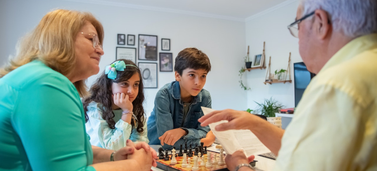 Grandparents with two of their grandchildren playing chess.