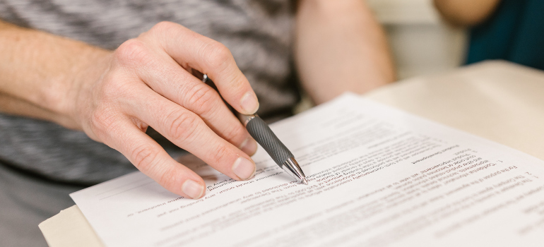 A close-up of a document and someone going through it while holding a pen.