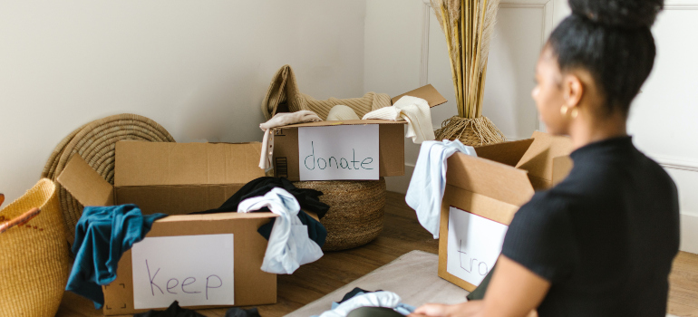 A woman decluttering her belongings before deciding whether she should opt for flat-rate movers vs. hourly movers.