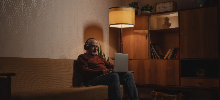 An image of a man wearing headphones while working on his laptop.