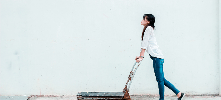 A woman pushing a moving dolly.