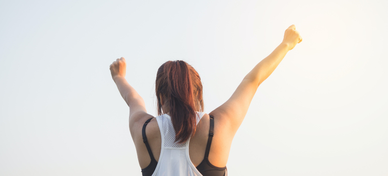 A woman with her hands up as if celebrating a victory.