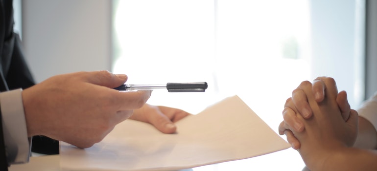 Businessman giving a contract and a pen to a person and using important relocation terms