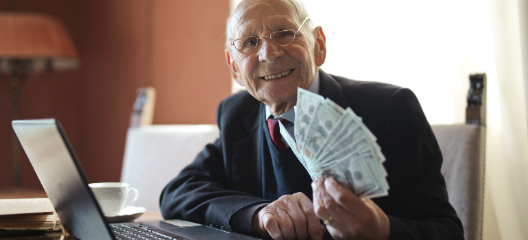 an elderly man holding a bunch of dollar bills and smiling
