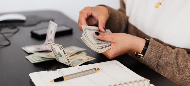 a woman counting money next to a notebook and a pen before moving from Sterling to Arlington