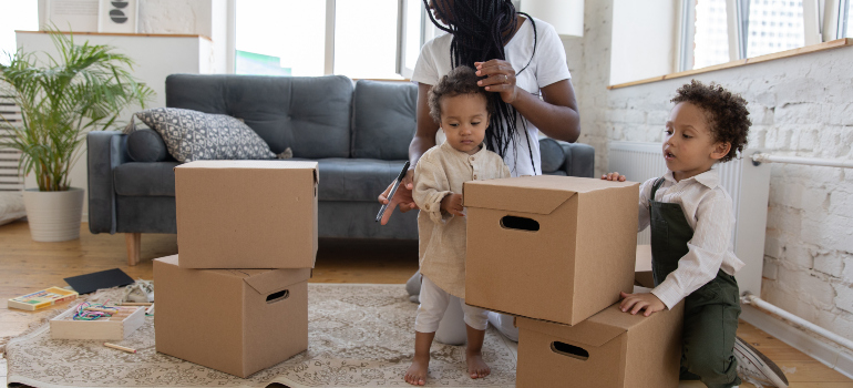 a woman looking after two kids that are observing cardboard boxes