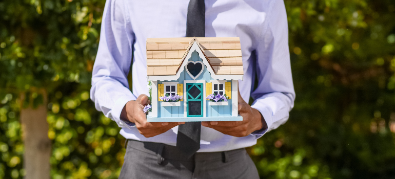 a man holding a model of a house