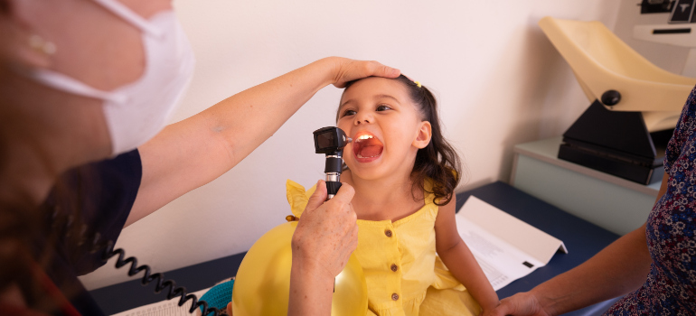 a doctor examining a little girl's throat