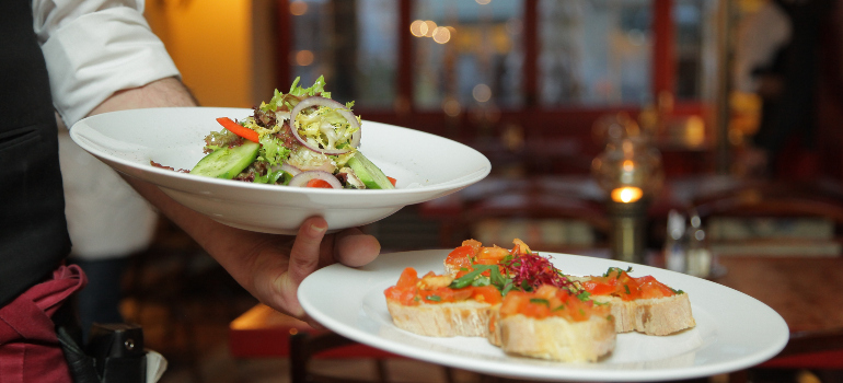 a waiter carrying two nicely arranged dishes