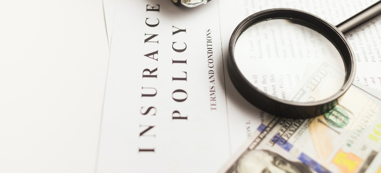 a magnifying glass and a dollar bill on top of an insurance policy