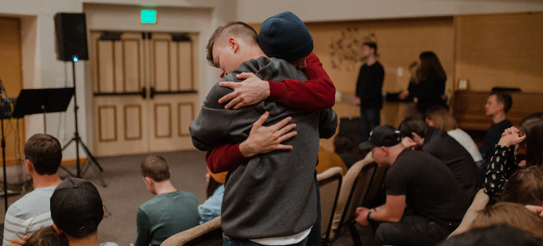 two people hugging at a support group meeting, the access to which can be one of the reasons why moving after rehab is a good idea