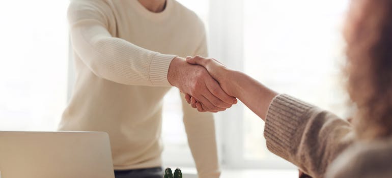 two people shaking hands after one of them just got a job