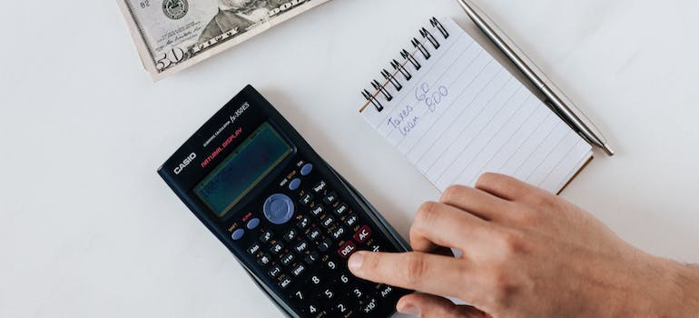 a person using a calculator and a notepad to create their new budget before moving to Ashburn after divorce