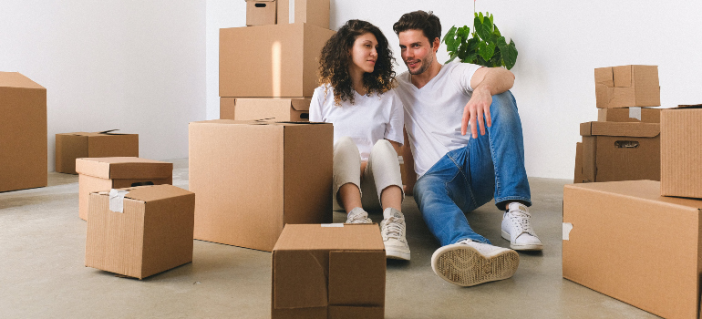 two people sitting in front of a pile of cardboard boxes