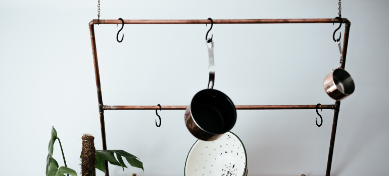 a rack hanging from the ceiling and holding several pots