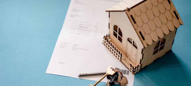 a wooden house and a house key on top of a piece of paper