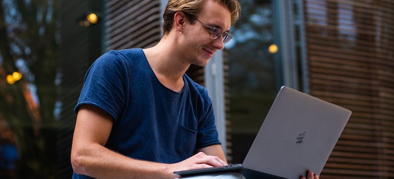 a man with glasses smiling when working on his laptop