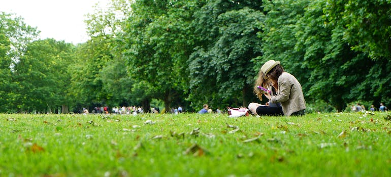 a girl sitting on the grass in some park while trying to live a fulfilling life in Sterling