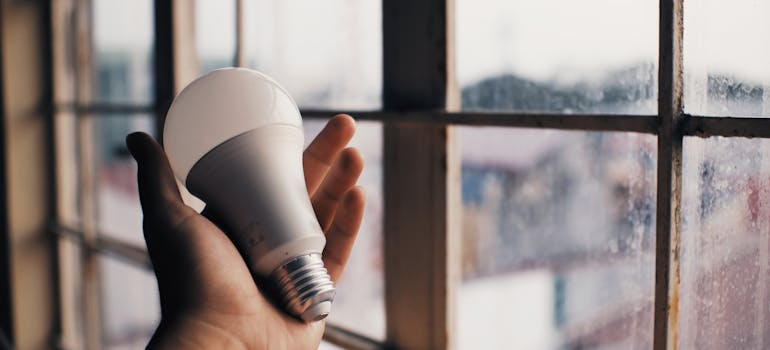 a perslon holding an LED light bulb which you should consider if you want to make your new Washington DC home eco-friendly