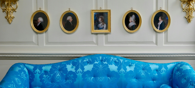 a blue sofa and 5 portraits above it