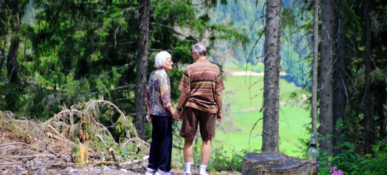 two seniors holding hands in a forest