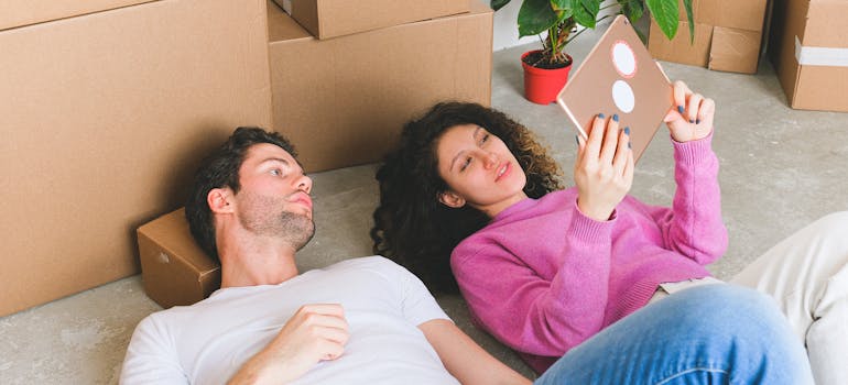 two people lying on the floor and making plans together, which you should do too after moving in with your partner