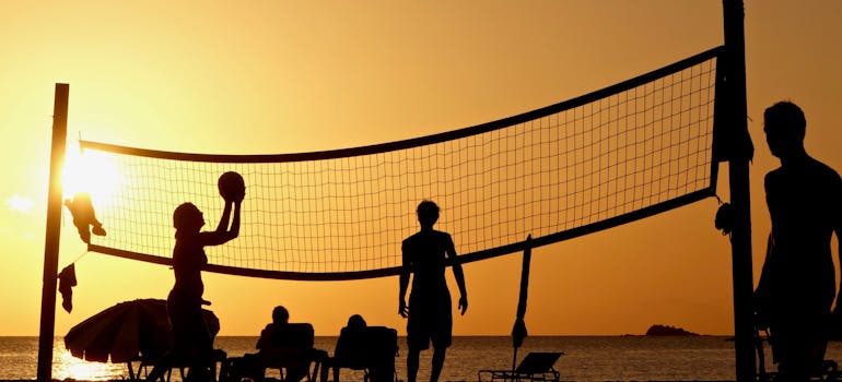 people playing beach volleyball at sunset