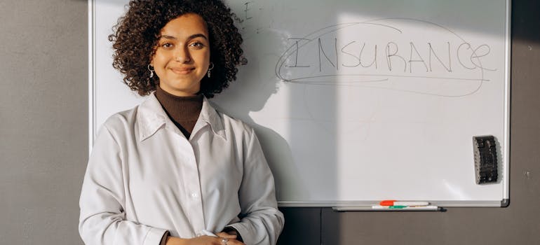 a woman standing in front of the word "insurance" written on a whiteboard