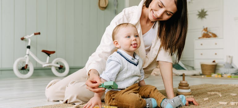 a woman smiling at her son while they are sitting on the floor