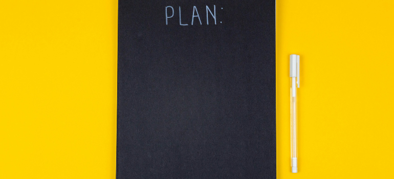 a black notebook with the word "plan" written on it and a pen next to it