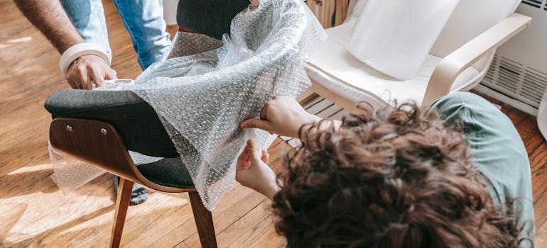 two people wrapping a chair with bubble packs