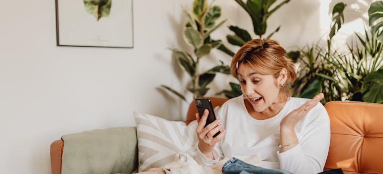 a woman who seems very happy after talking to a potential landlord on the phone