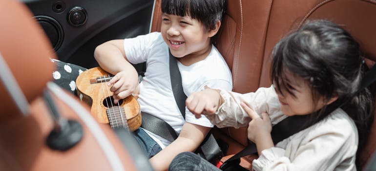 two kids playing a guitar in a car while moving to Falls Church with a newborn