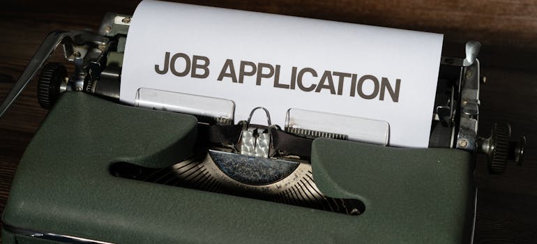 a typewriter with a piece of paper in it holding the headline "Job application"