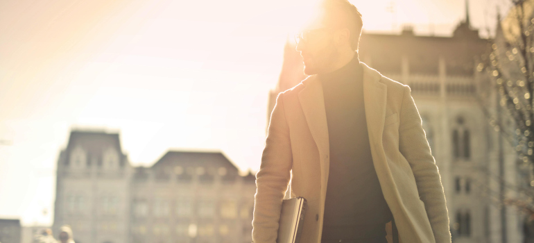 a man in a coat carrying a laptop