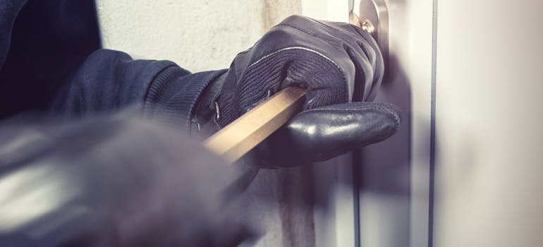 a person forcing open a door by using a metal bar