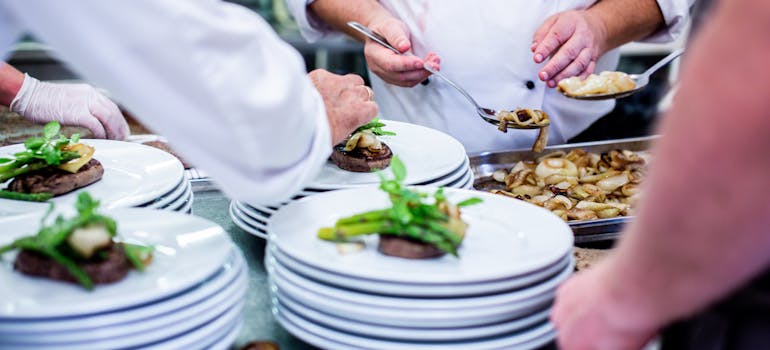 several chefs preparing plates with food 