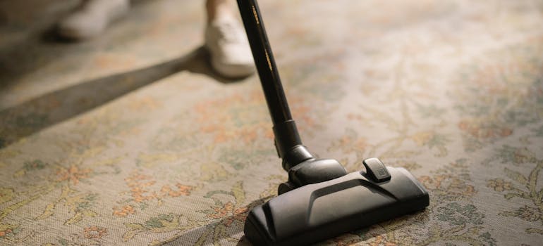 a person vacuuming a pale carpet