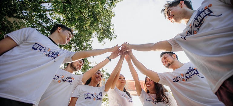 several people wearing the same shirts putting their hands together