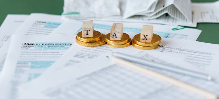 cubes spelling the word "tax" on top of some papers and coins