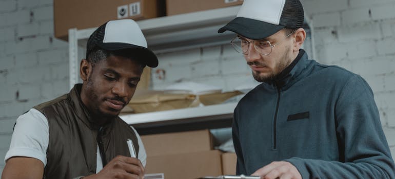 A mover and a client discussing the things you need to know about moving insurance over a cardboard box